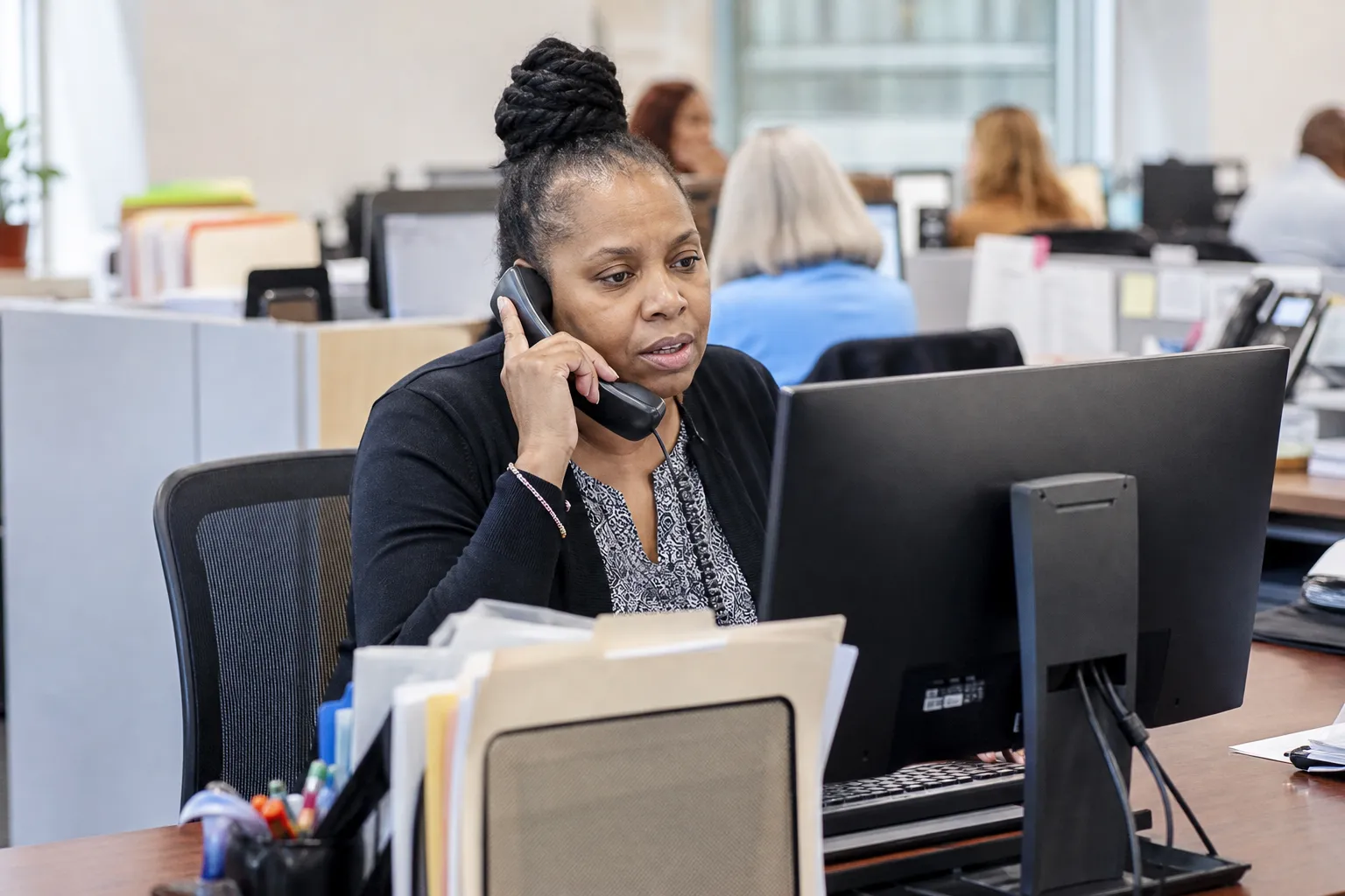 Government office worker at desk handling a phone call with computer visible